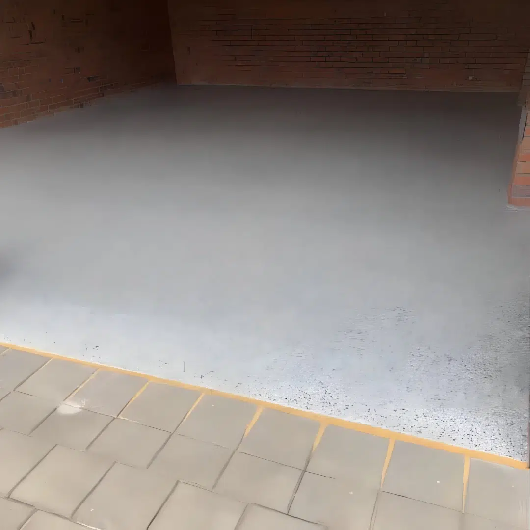 Freshly coated epoxy garage floor next to a brick wall and paver driveway