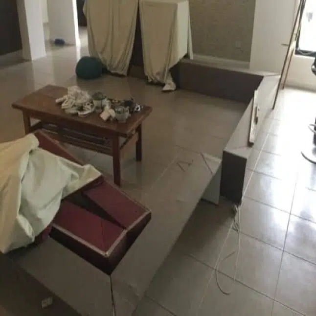 Minimalist living room under renovation with a sunken seating area tiled floors a low wooden coffee table and furniture covered with sheets