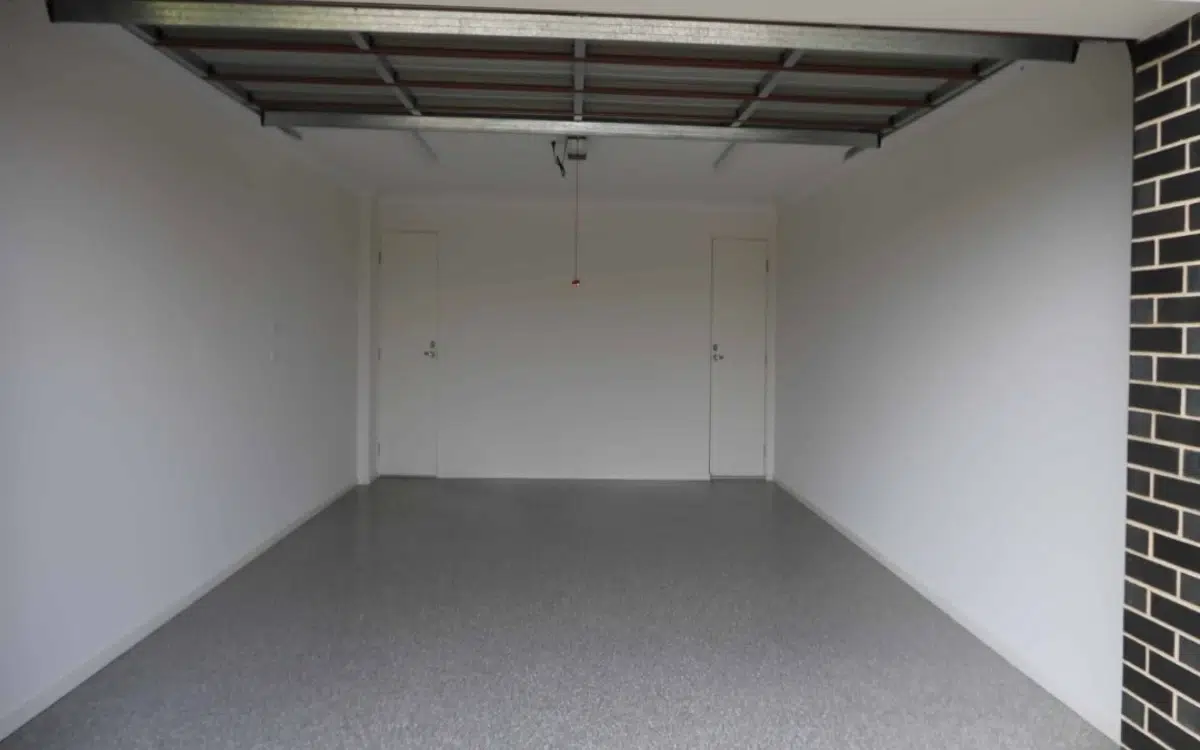 Open empty two car garage with a clean epoxy floor and two white doors at the back