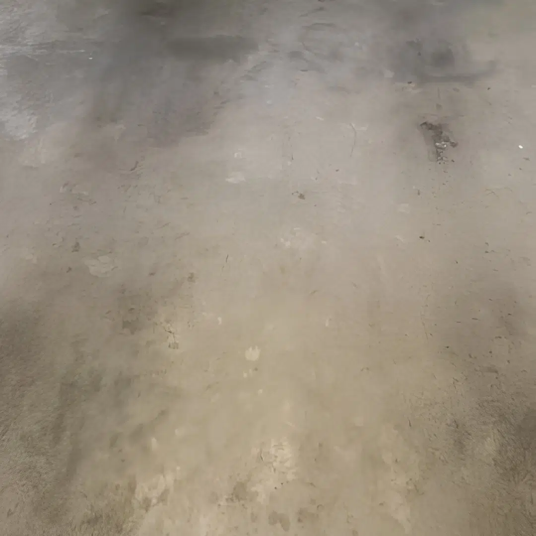 Stained unfinished concrete floor with patches and discoloration
